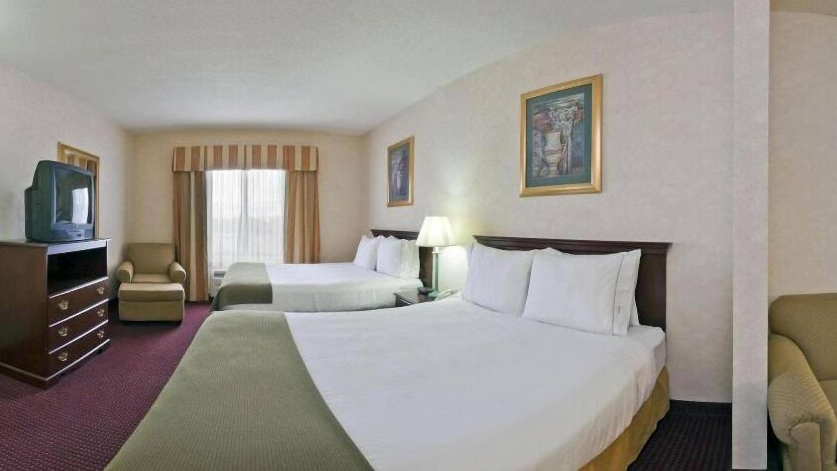 Una habitación de hotel con dos camas, televisión, escritorio y una silla.