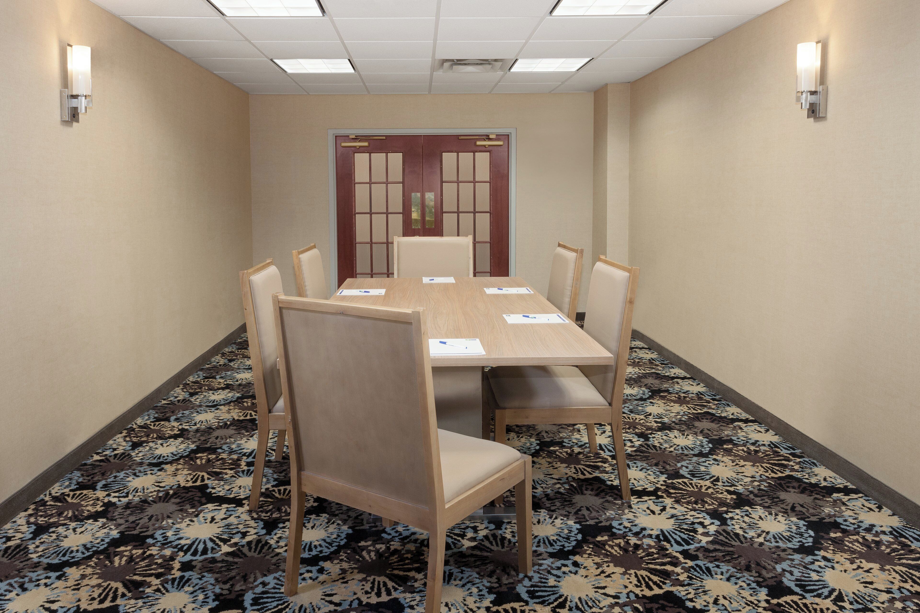 A conference room with a long table, six chairs, and a door with a decorative panel.