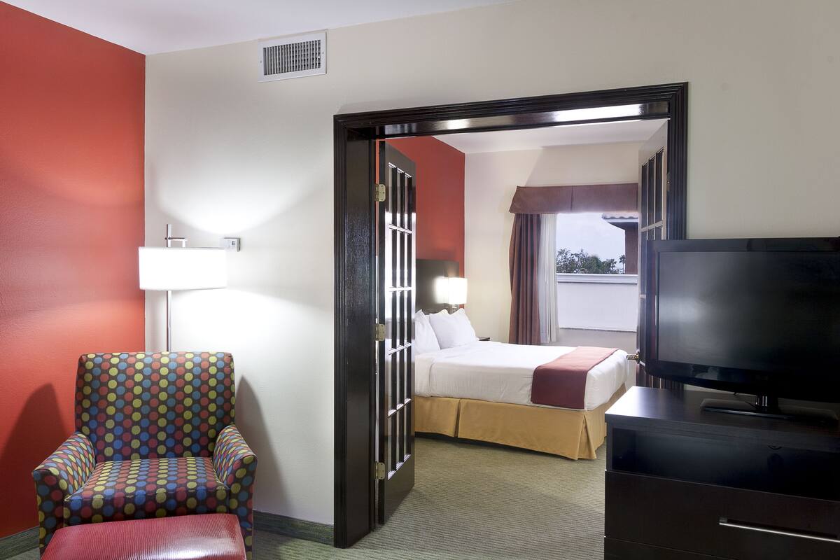 A hotel room with a bed, a TV, a chair, and a lamp.