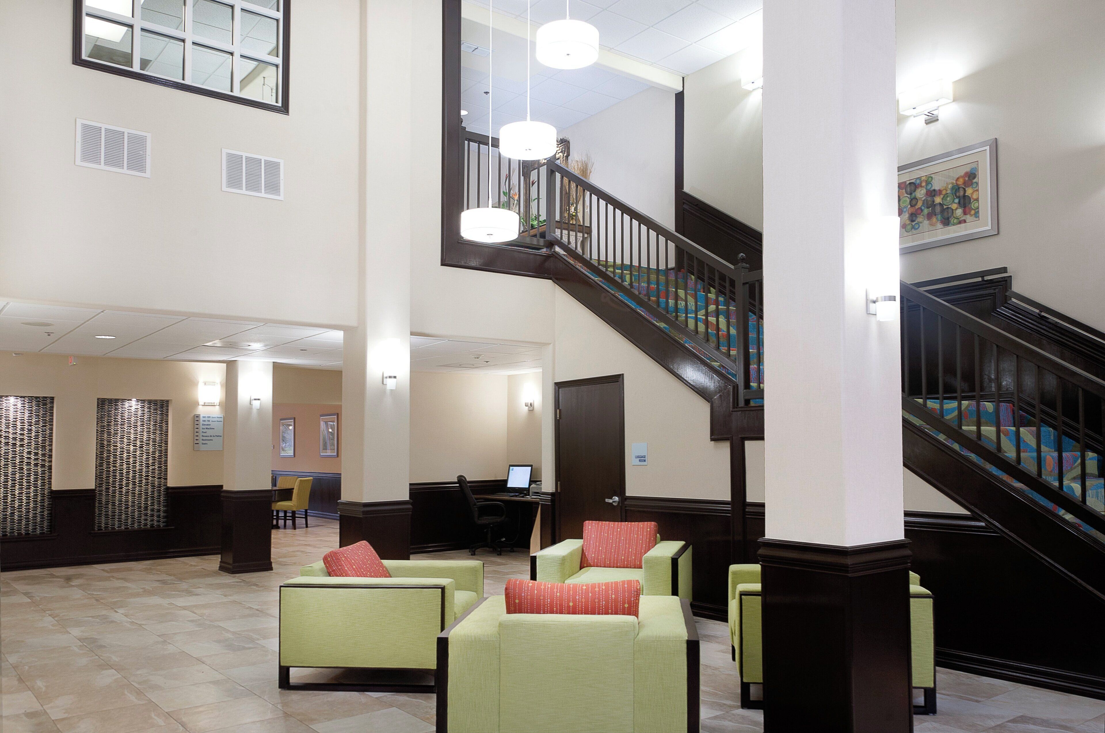 A lobby with a staircase, seating area, and a reception desk.