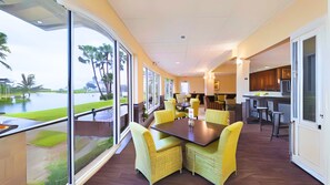 Une chambre d’hôtel moderne dotée d’un coin repas, de grandes fenêtres et d’une vue sur une étendue d’eau.