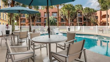 Una piscina al aire libre, sombrillas, sillones reclinables de piscina