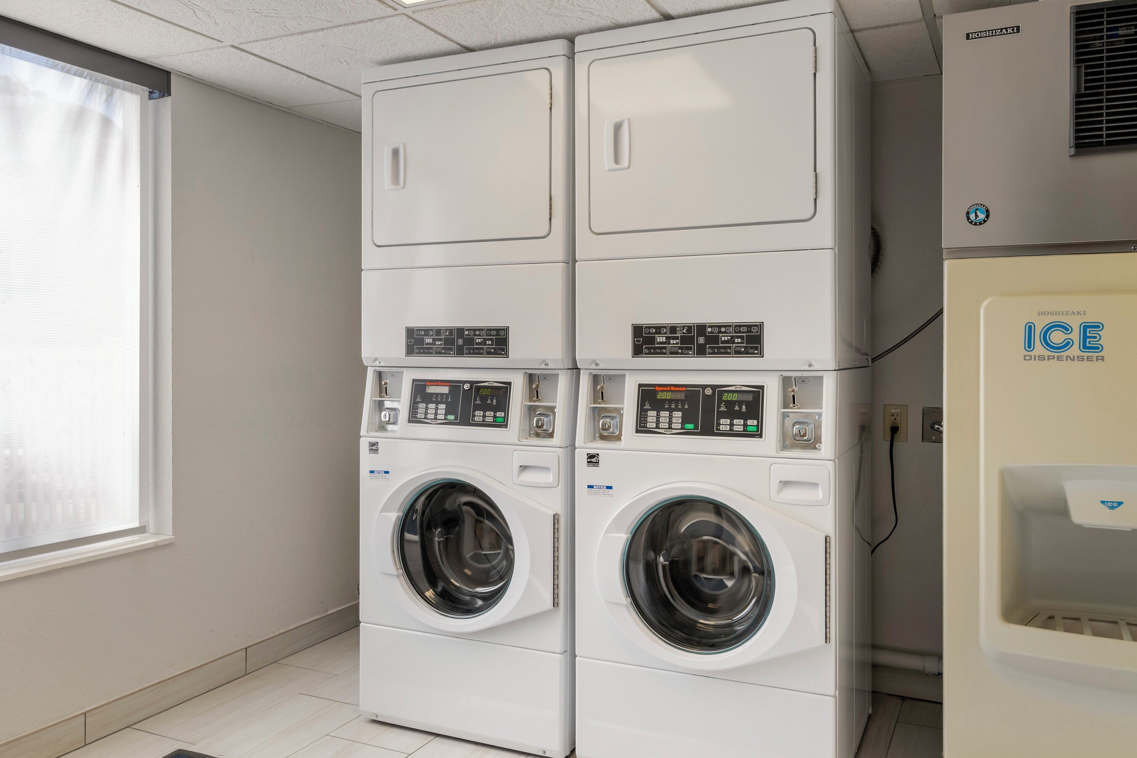 A laundry room with two stacked front-loading washing machines and an ice dispenser.