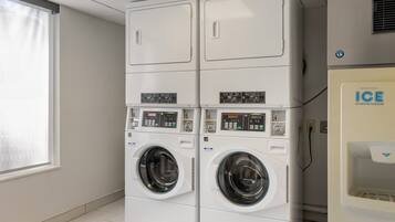 A laundry room with two stacked front-loading washing machines and an ice dispenser.