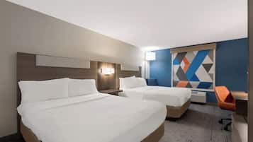 A hotel room with two beds, a desk, and a chair.