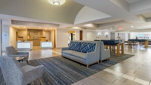 A spacious lobby with a reception desk, seating area, and a dining section. - Holiday Inn Express Hotel & Suites The Villages by IHG (Lady Lake)