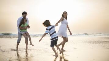 Family strolls along the beach, enjoying the warm glow of the setting sun.
