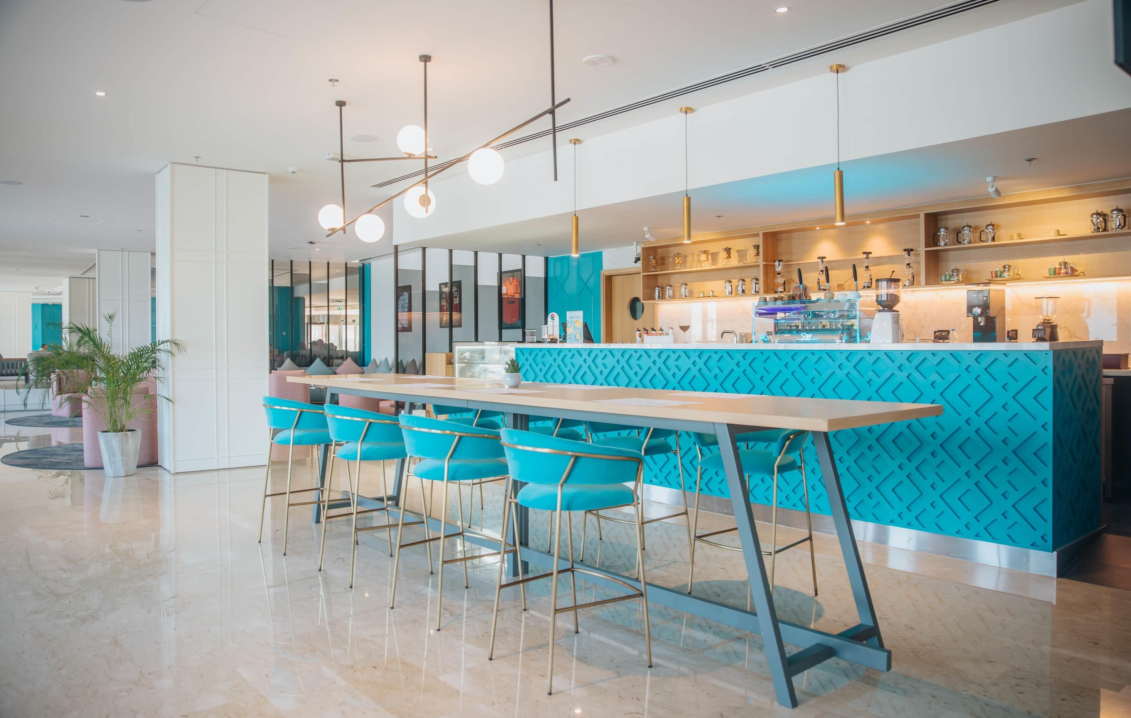 A modern bar area with a teal patterned counter, bar stools, and pendant lighting.