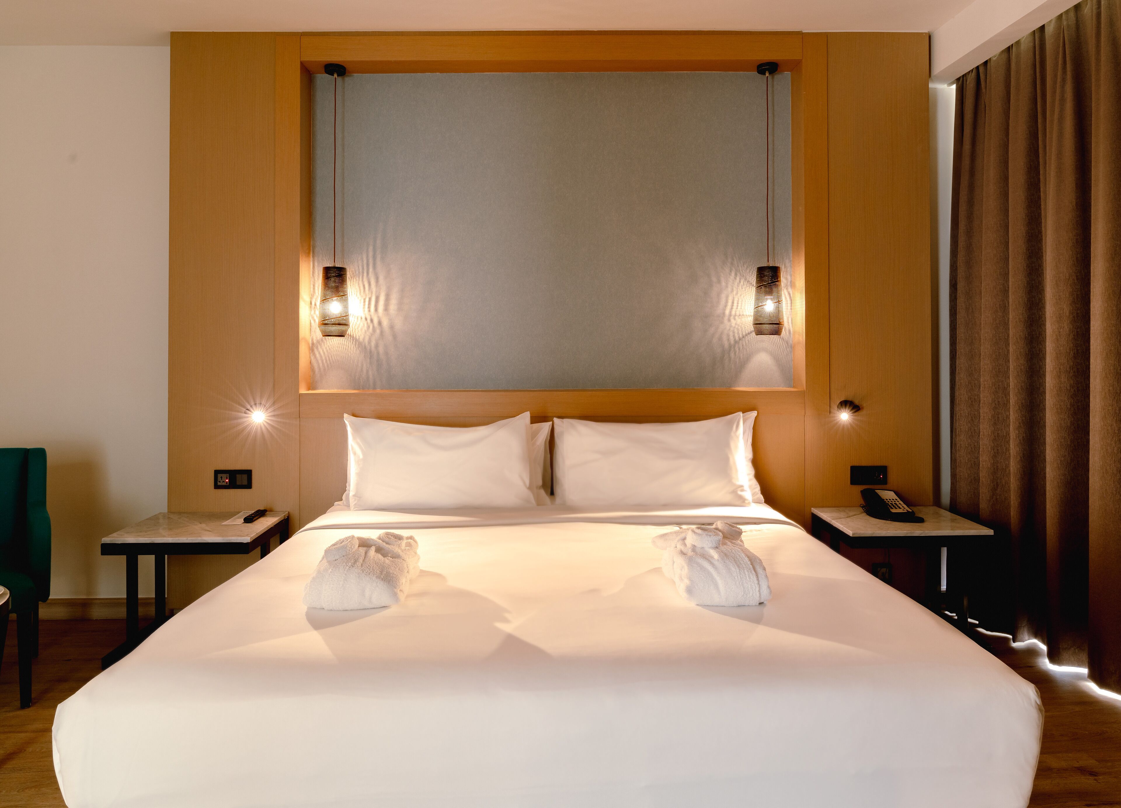 A hotel room with a large bed, two bedside tables, a telephone, and a wall-mounted light fixture.