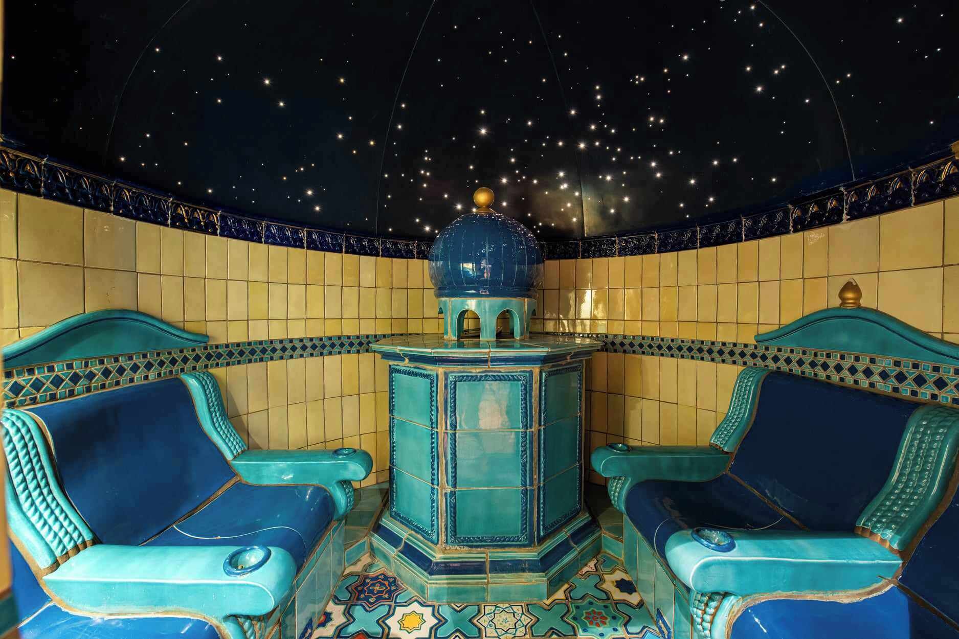 A room with two blue chairs, a central blue table, and a starry ceiling.