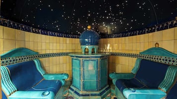 A room with two blue chairs, a central blue table, and a starry ceiling.