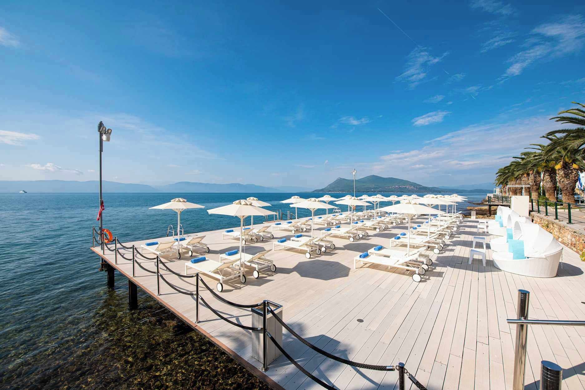 A deck with sun loungers and umbrellas overlooking the sea.