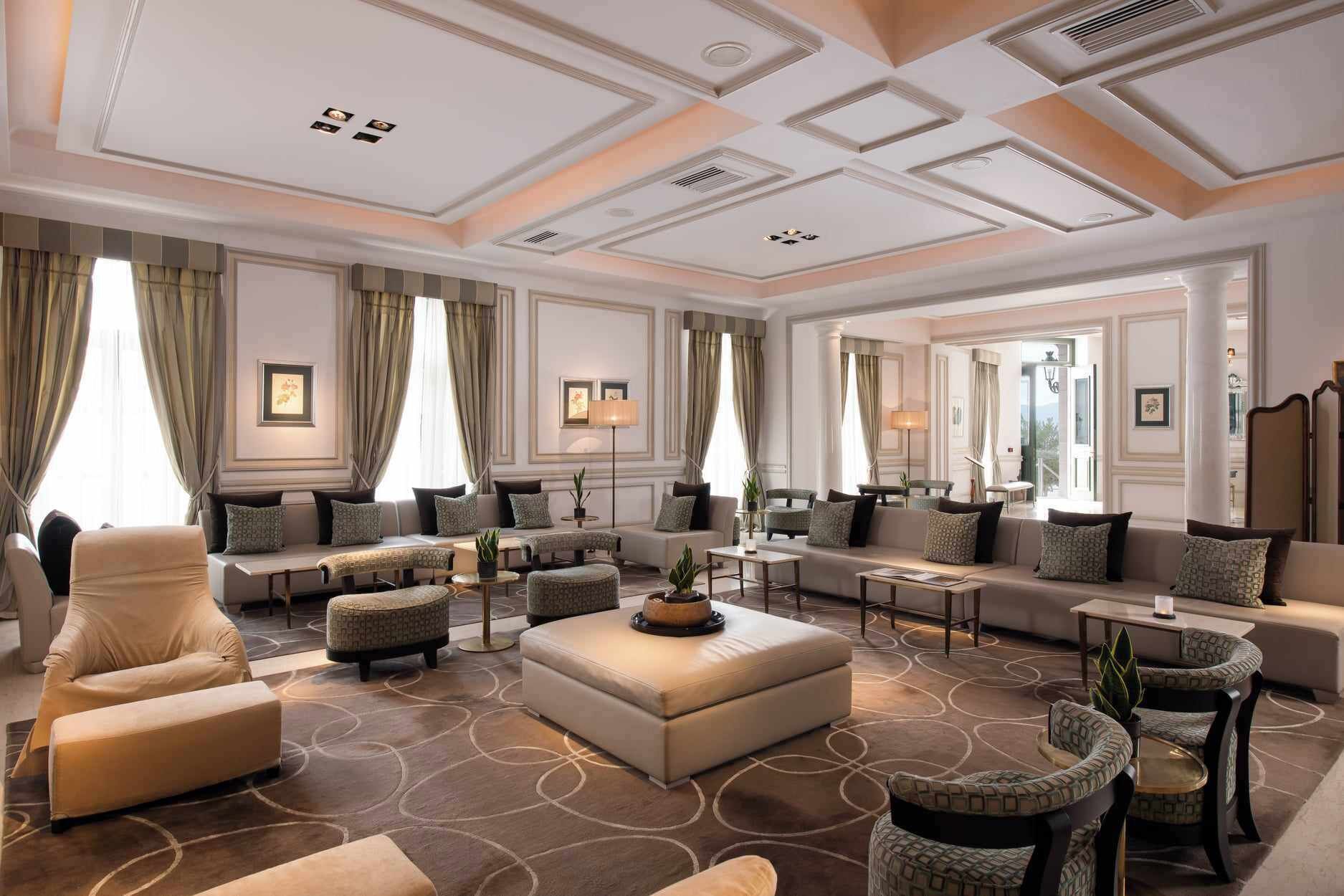 Un hall d’hôtel spacieux, doté de plusieurs espaces salon, d’un grand miroir et d’un plafond pourvu d’un éclairage encastré.