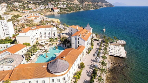 A coastal resort with a swimming pool, beachfront villas, and a pier.