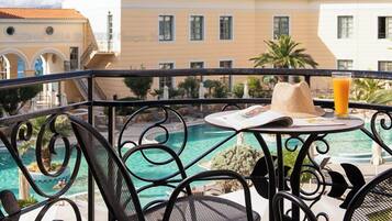 A poolside area with outdoor seating, a clear view of a building with a tiled roof, and a clear blue sky.