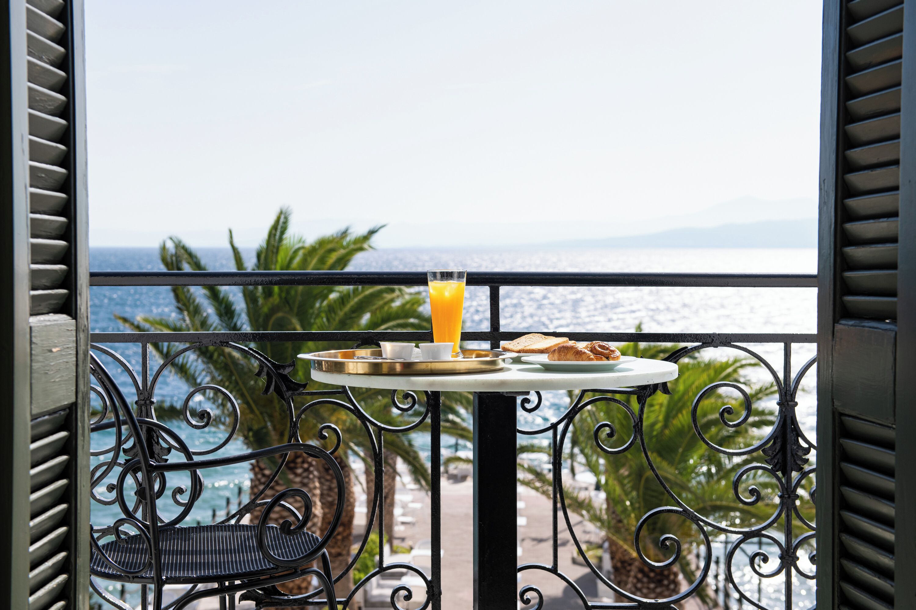 Un balcon avec une table préparée pour le petit-déjeuner, donnant sur une étendue d’eau.