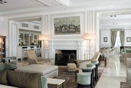 A spacious hotel lobby with a fireplace, comfortable seating, and a dining area.