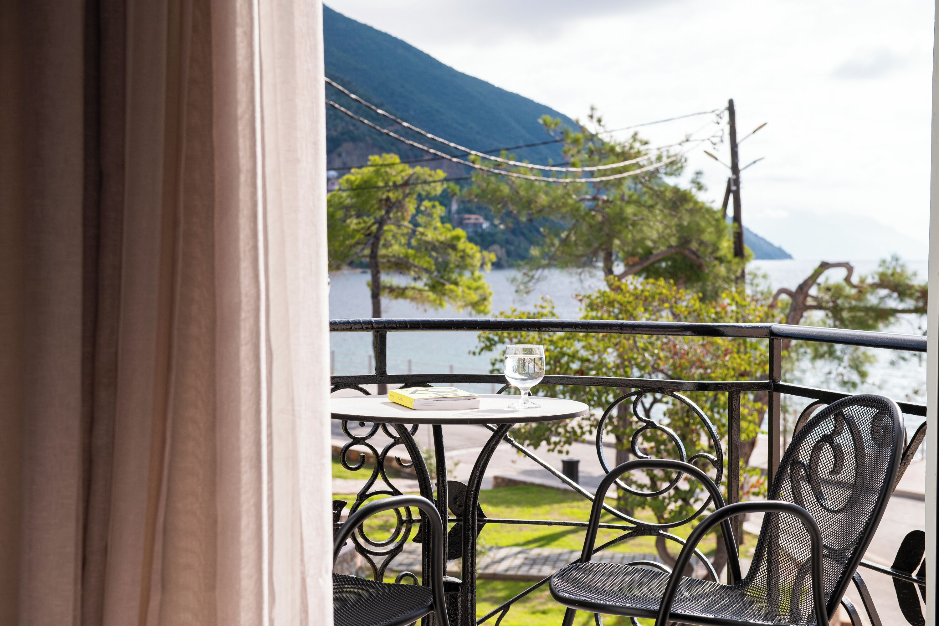 A balcony with a table and chairs, overlooking a body of water and greenery.