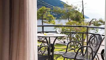 A balcony with a table and chairs, overlooking a body of water and greenery.
