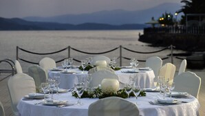 A table set for a formal dinner with a view of the sea and mountains in the background.