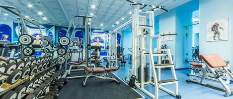 A gym with various exercise equipment, including dumbbells, weight machines, and benches.