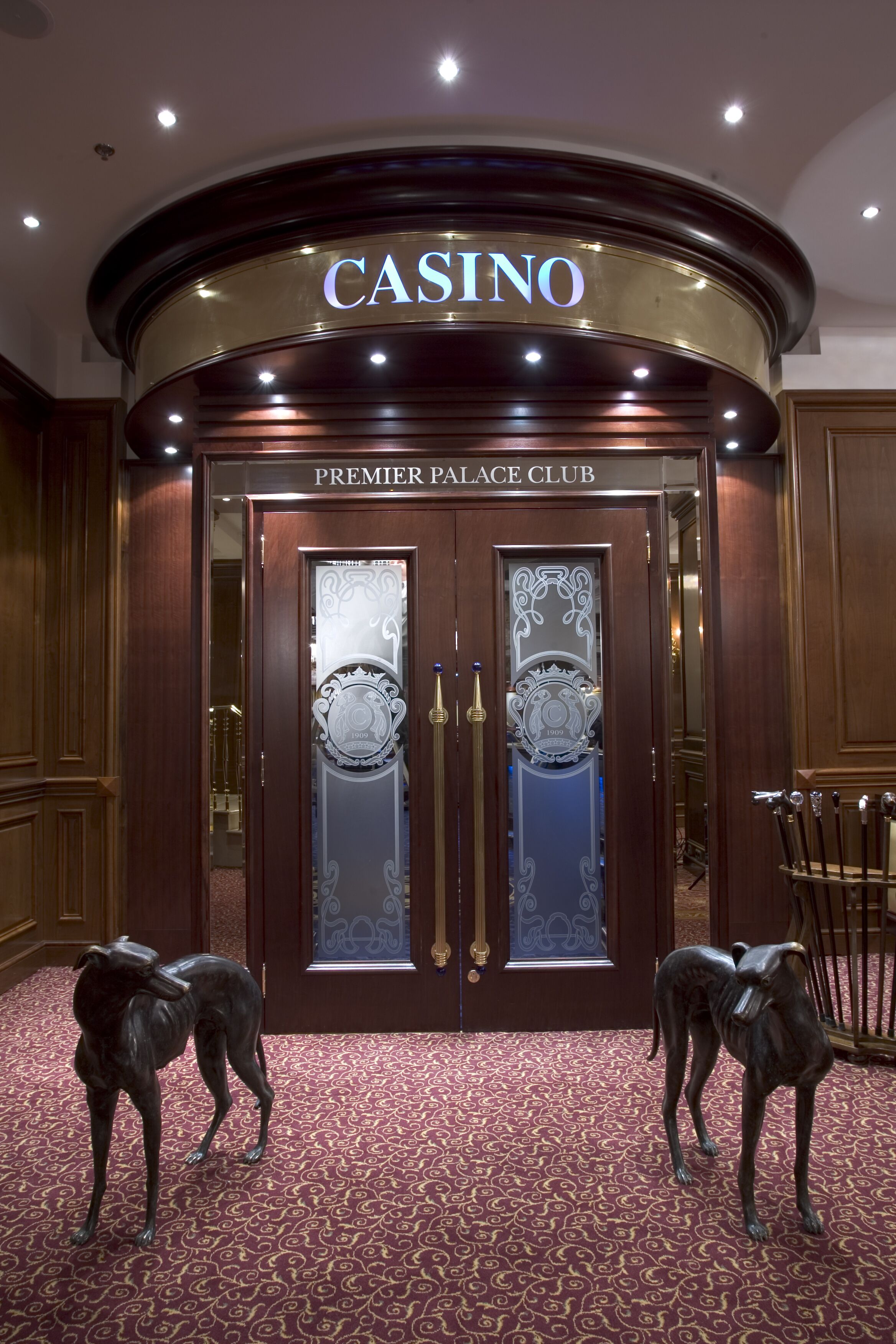 La entrada al Premier Palace Club, un casino con fachada de madera oscura y dos puertas de cristal con diseños intrincados.