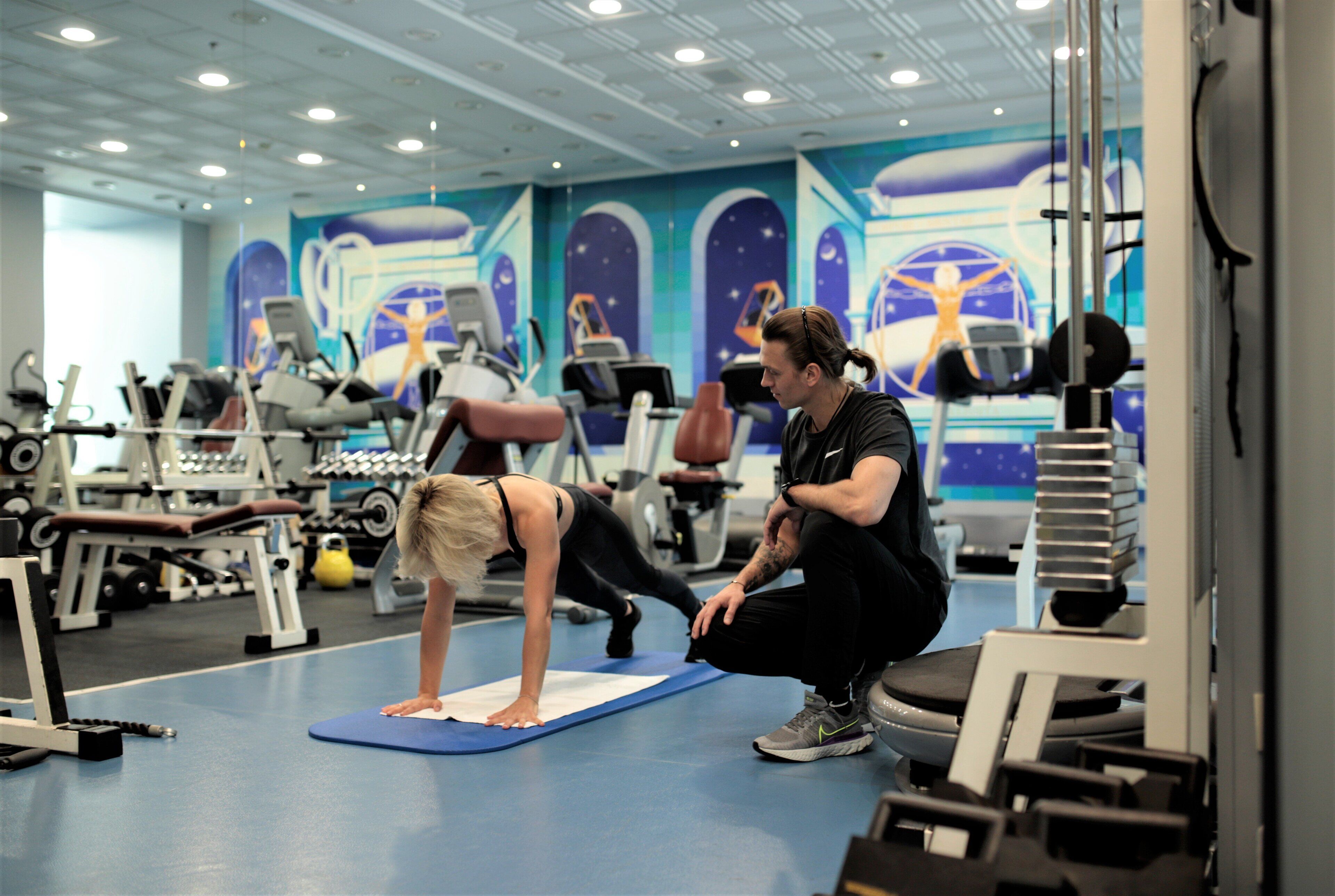 Un gimnasio con equipo de ejercicio, una colchoneta azul y un mural en la pared.