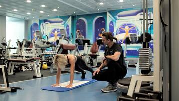 Un gimnasio con equipo de ejercicio, una colchoneta azul y un mural en la pared.