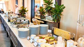 Ein reichhaltiges Buffet mit verschiedenen Speisen und Gerichten, darunter Teller, Schüsseln und eine Käseplatte.