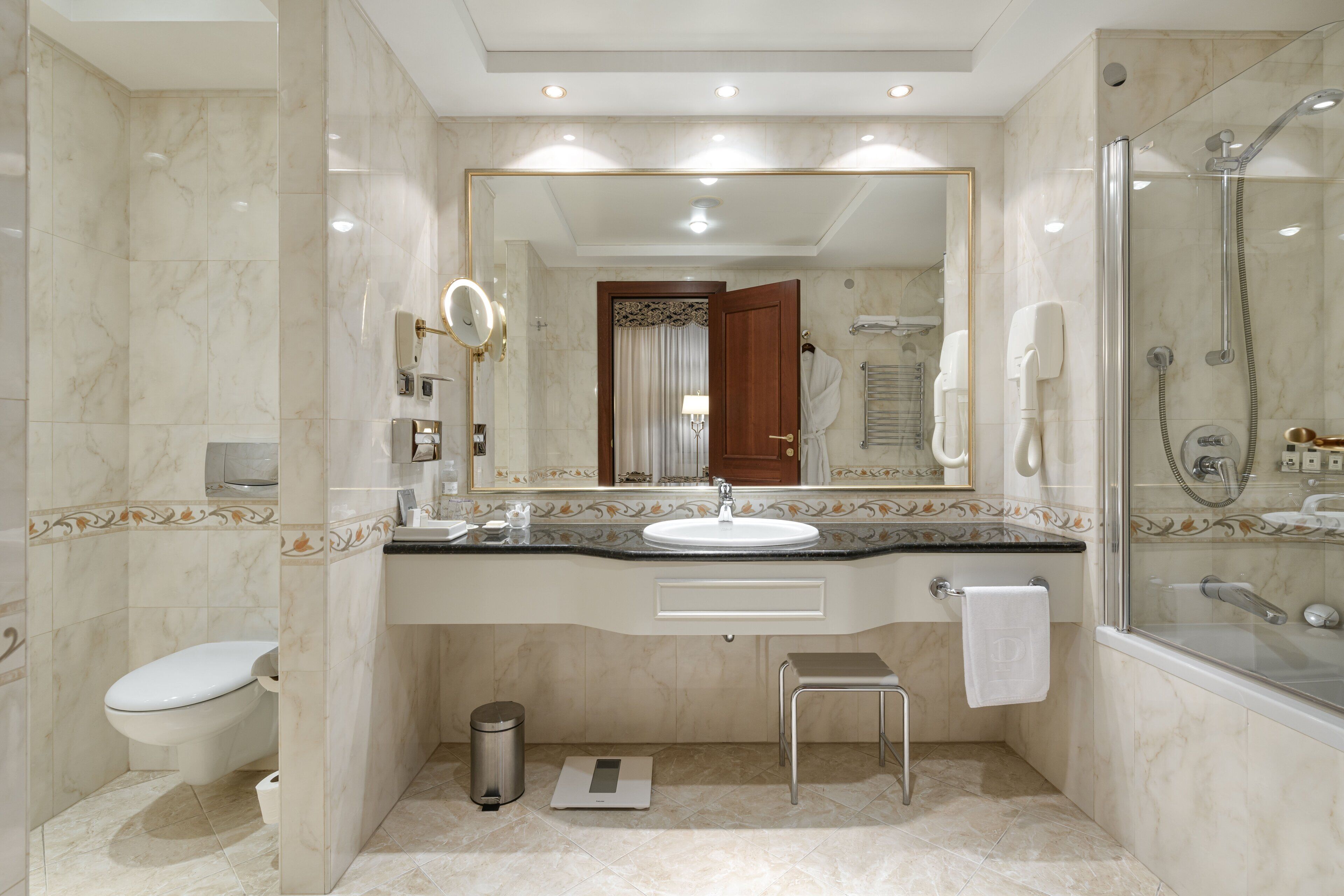 A modern bathroom with a marble sink, a glass-enclosed shower, and a large mirror.