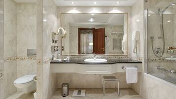 A modern bathroom with a marble sink, a glass-enclosed shower, and a large mirror.