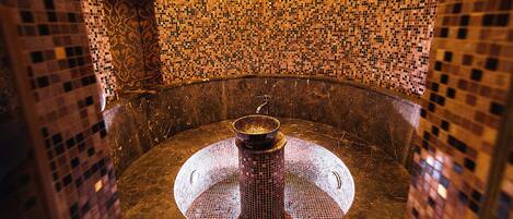 A circular room with mosaic walls and a central fountain.