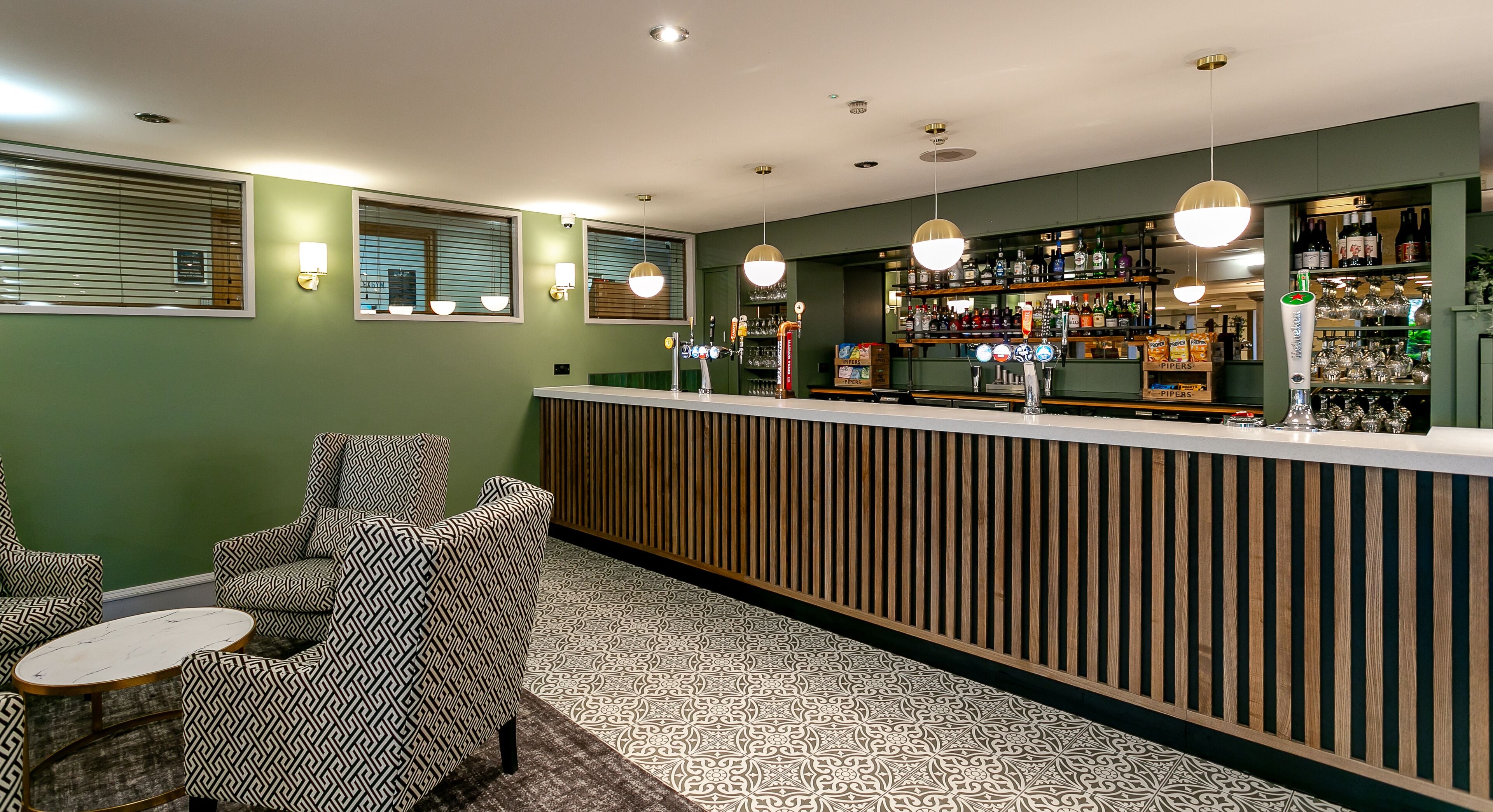 A bar area with a wooden counter, patterned chairs, and a tiled floor.