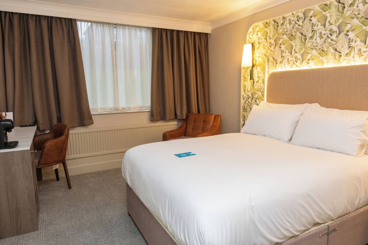 Una habitación de hotel con una cama, un escritorio y una silla.