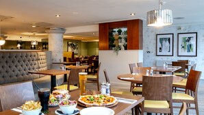 Un restaurante con diferentes opciones de asientos, como cabinas y mesas, y una pizza sobre la mesa.