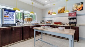 Una cocina moderna con refrigerador, máquina de café y dispensador de jugo.