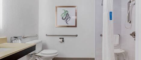 A bathroom with a toilet, sink, shower, and a framed artwork on the wall.
