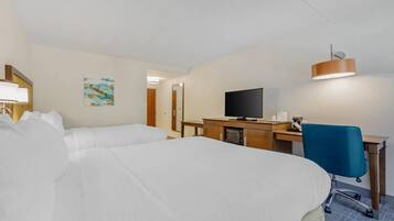 A hotel room with a bed, desk, television, and a blue chair.