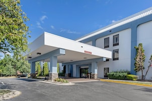 Un edificio moderno con entrada cubierta, señalización clara y zona de estacionamiento.