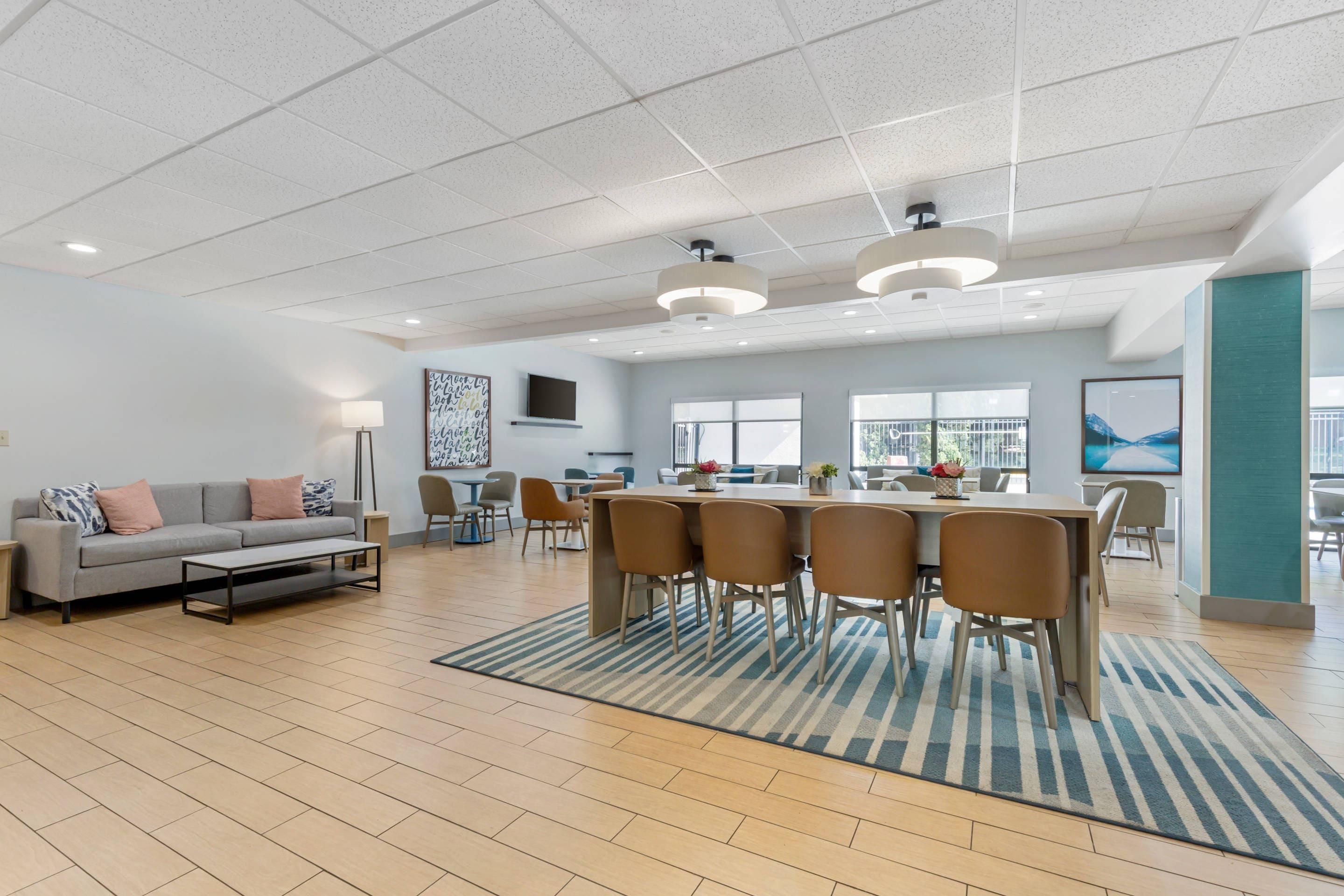 A spacious living area with a sofa, coffee table, dining table with chairs, and a large window.