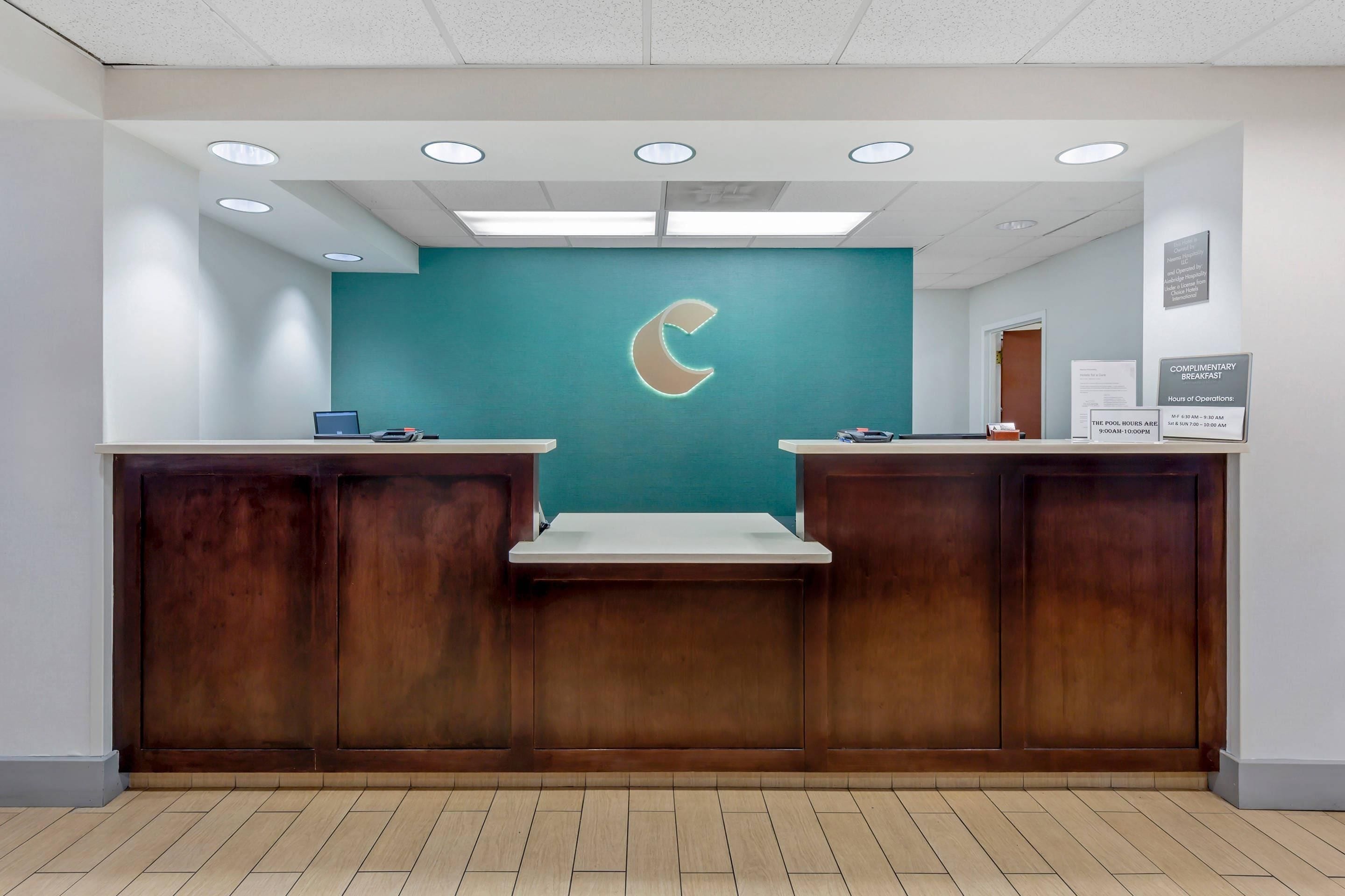 A reception desk with a teal wall and a crescent moon logo, wooden panels, and a tiled floor.