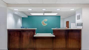 Un mostrador de recepción con una pared verde azulado y un logotipo de luna creciente, paneles de madera y suelo de baldosas.