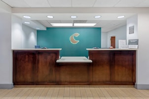 A reception desk with a teal wall and a crescent moon logo, wooden panels, and a tiled floor.