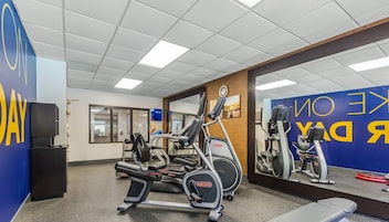 Un gimnasio con máquinas de cardio, un espejo y una pared azul con texto.