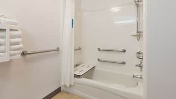 A bathroom with a white bathtub, a shower, and a towel rack with folded towels.