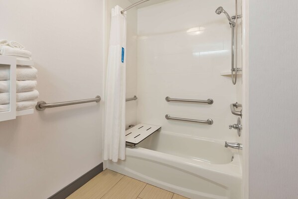 Un baño con una bañera blanca, ducha y un perchero con toallas dobladas.