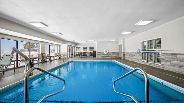 An indoor swimming pool with clear blue water, surrounded by lounge chairs and a stone wall. - Hampton Inn Bloomington West (Bloomington)