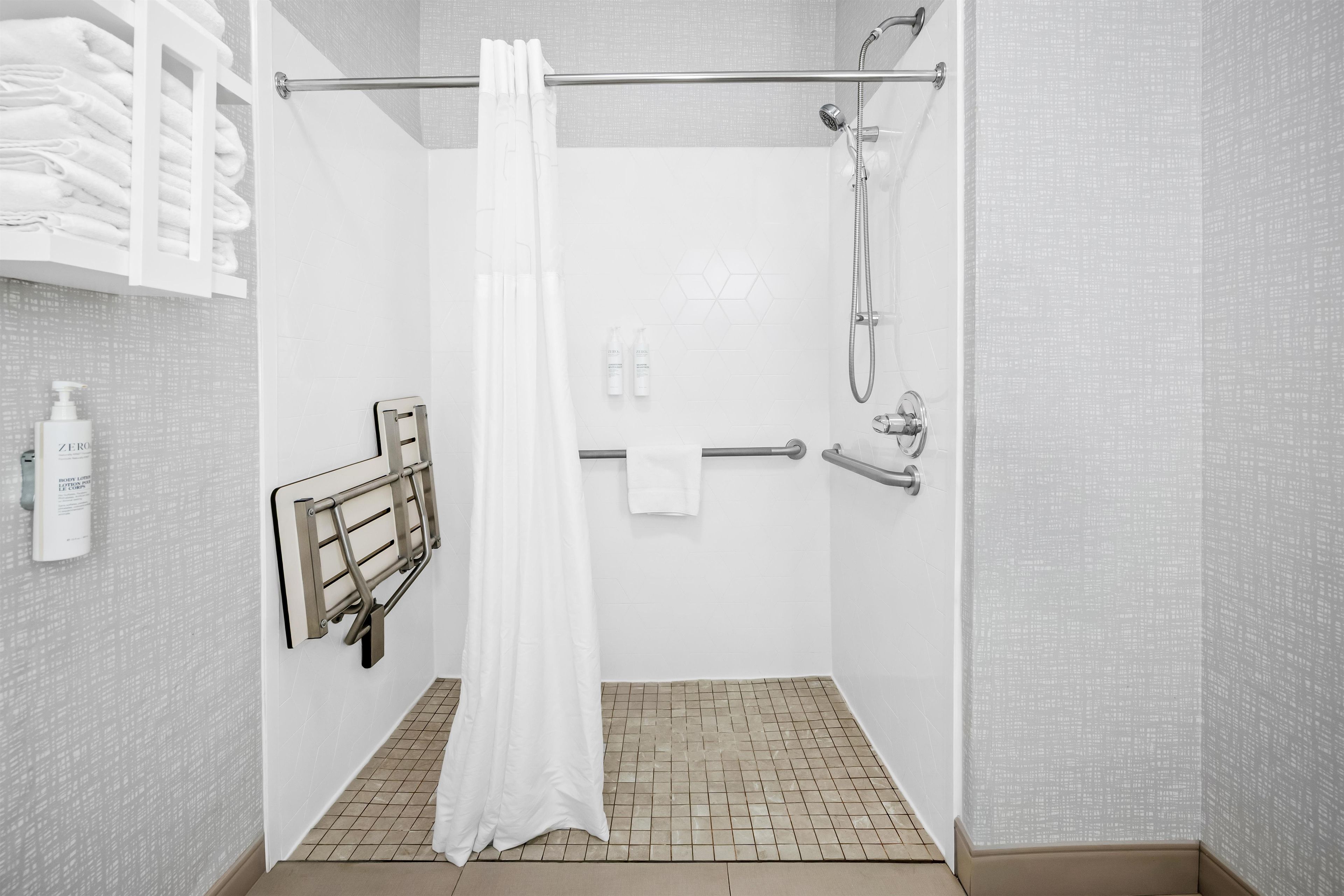 A modern shower area with a glass door, a towel rack, and a showerhead.