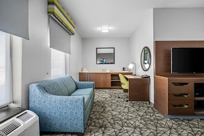 Habitación de hotel moderna con sofá, escritorio, televisión de pantalla plana y piso estampado.