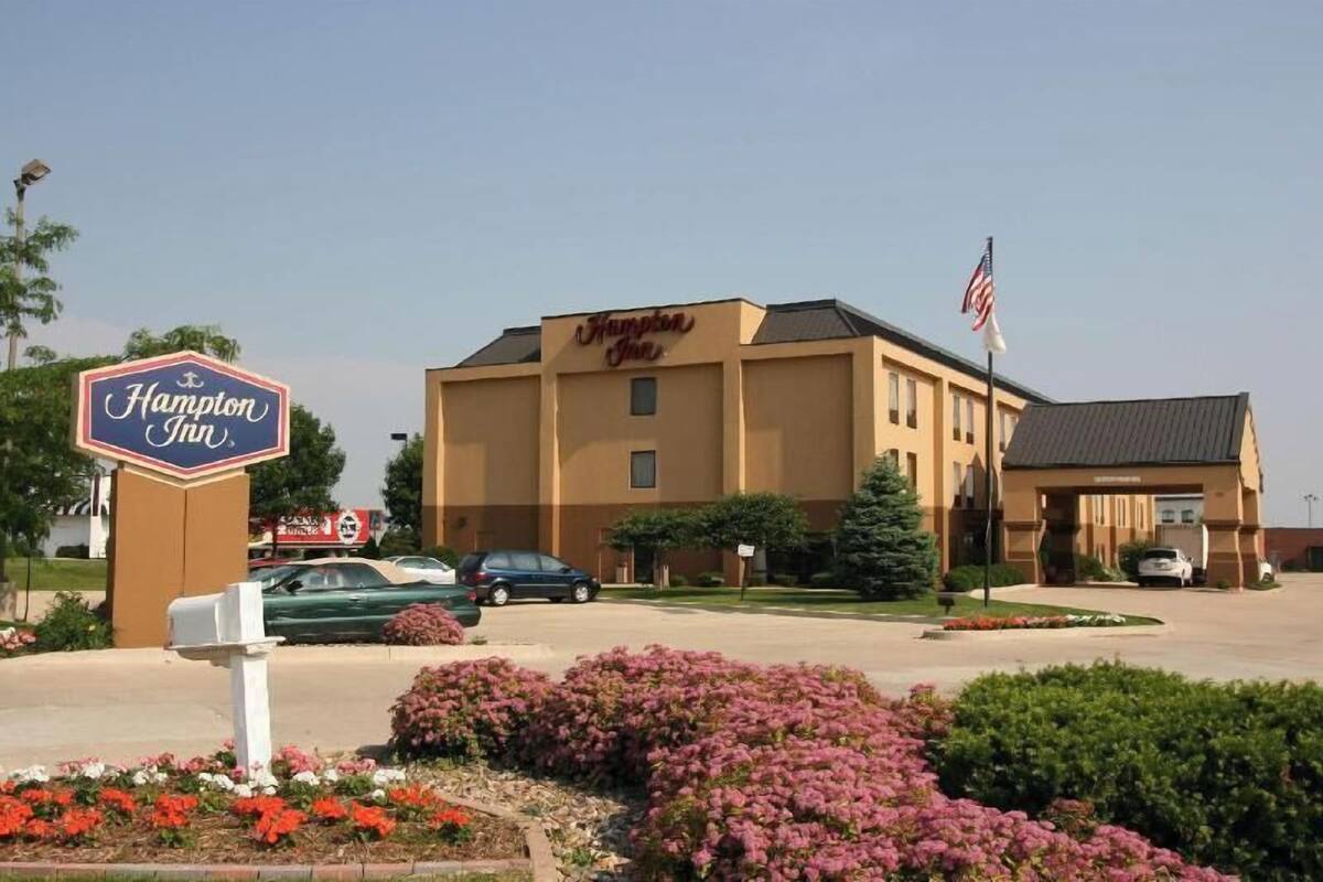 A Hampton Inn hotel with a sign, parking lot, and landscaping.